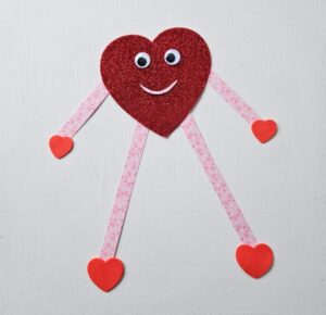 Heart craft for Valentine's Day built with a big red heart, googly eyes, strips of paper, and smaller hearts